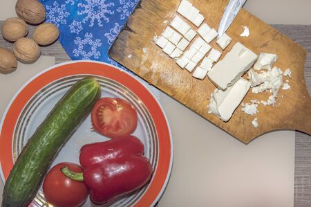 A variety of ingredients for the preparation of vegetable salad with cheese lie on the table.の写真素材