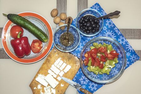 A variety of ingredients for the preparation of vegetable salad with cheese lie on the table.の写真素材