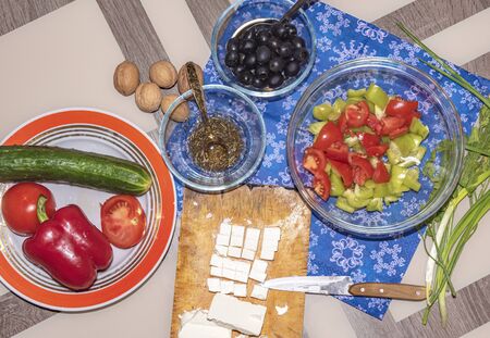 A variety of ingredients for the preparation of vegetable salad with cheese lie on the table.の写真素材