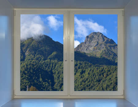 Blue sky and mountain peaks in the clouds can be seen from the window.