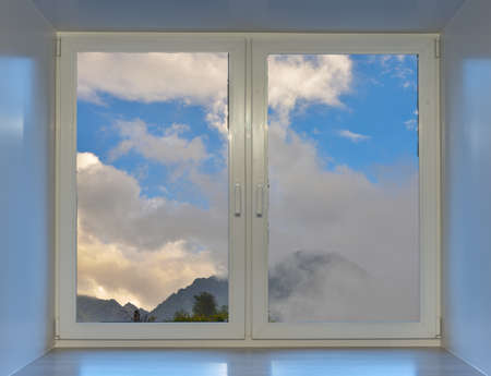 Blue sky and mountain peaks in the clouds can be seen from the window.