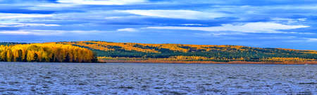 Autumn landscape is visible on the right bank of the pond, where yellow colors prevail.の写真素材