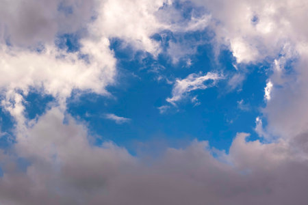 Landscape of blue sky with cumulus white clouds and dark rainy clouds on a summer day.の写真素材