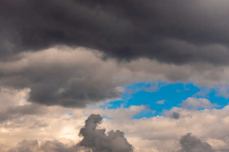 Landscape of blue sky with cumulus white clouds and dark rainy clouds on a summer day.の写真素材