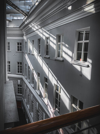 A vertical shot of the facade of a building with windows and blinds
