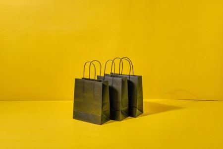 Black shopping bags on a yellow backgroundの素材
