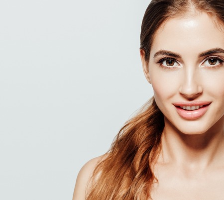 Beauty Woman face Portrait. Beautiful model Girl with Perfect Fresh Clean Skin. Youth and Skin Care Concept. Isolated on a gray backgroundの写真素材
