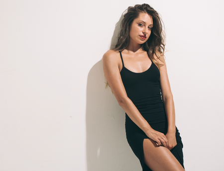 Fashion woman portrait sexy in black dress hot summer near white backgroundの写真素材