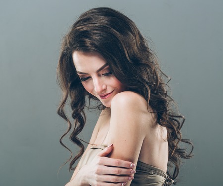 Woman face with curly hair on gray background close up portraitの写真素材