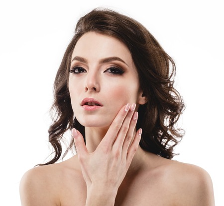 Beautiful woman face portrait with curly flying hair studio on white touching faceの写真素材