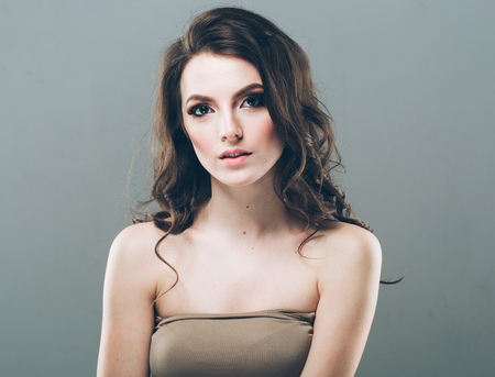 Woman face with curly hair on gray background close up portraitの写真素材