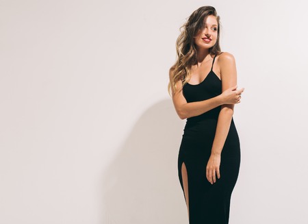 Fashion woman portrait sexy in black dress hot summer near white backgroundの写真素材