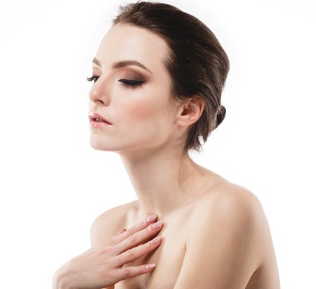 Beautiful woman face neck shoulders is touching her face. close up portrait young studio on whiteの写真素材