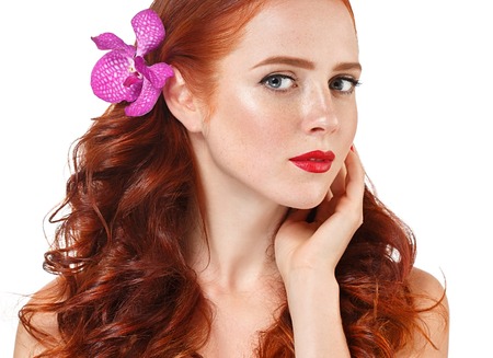 Beautiful woman portrait with flower in hair perfect make up manicure pink lips and nails on beige background isolatedの写真素材
