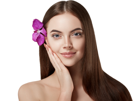Woman beautiful portrait with flower orchid in hair. Studio shot. Isolated on white.の写真素材