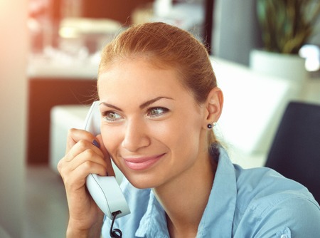 Serious business woman working in office talking on telephone. Idoor shot.の写真素材
