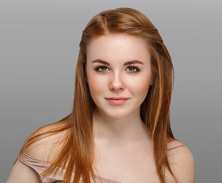 Beautiful woman face close up portrait young with red hair on gray background. Studio shot.の写真素材
