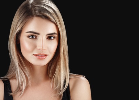 Woman blonde hair closeup beautiful skin portrait on black background.の写真素材