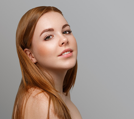 Beautiful woman face close up portrait young with red hair on gray background. Studio shot.の写真素材