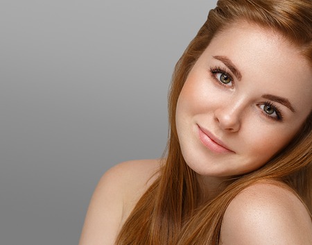 Beautiful woman face close up portrait young with red hair on gray background. Studio shot.の写真素材