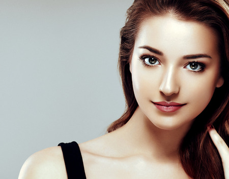Beautiful woman face close up portrait young. Studio shot. On gray background.の写真素材