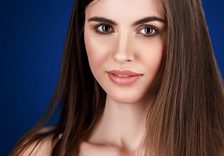 Fashion Beautiful woman portrait close up on blue background. Studio shot.の写真素材