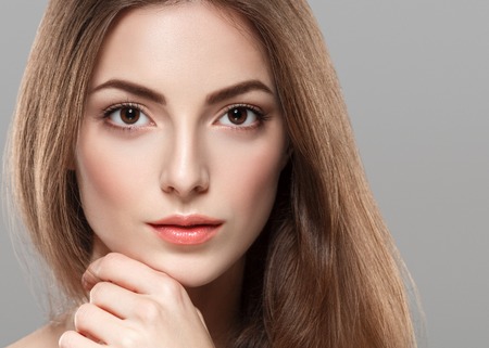 Young beautiful woman face portrait with healthy skin on gray background. Studio shot.の写真素材