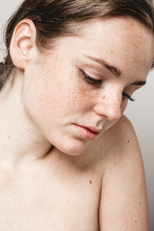 Young beautiful freckles woman face portrait with healthy skin. Studio shot.の写真素材