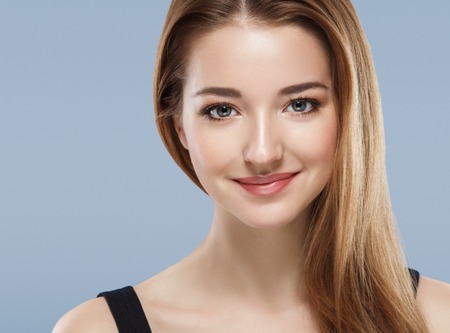 Beautiful woman face close up portrait young studio on blue. Studio shot.の写真素材