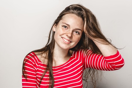 Beautiful young woman portrait freckles smiling posing attractive brunette. Studio shot. Isolated on gray.の写真素材