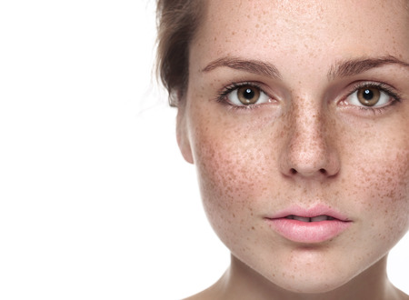 Young beautiful freckles woman face portrait with healthy skin. Studio shot. Isolated on white.の写真素材
