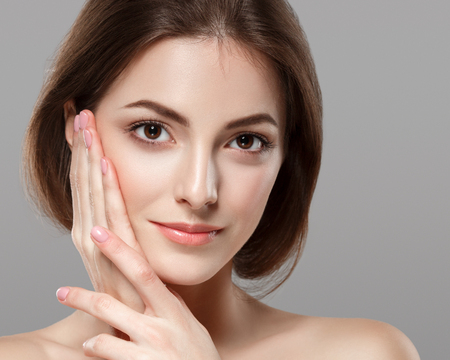 Young beautiful woman face portrait with healthy skin on gray background. Studio shot.の写真素材