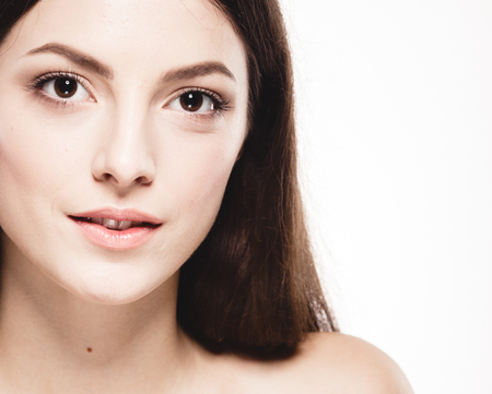 Beauty Woman face Portrait. Beautiful model Girl with Perfect Fresh Clean Skin. Brunette female looking at camera and smiling. Youth and Skin Care Concept. Isolated on a white backgroundの写真素材