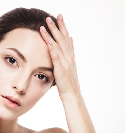 Beauty Woman face Portrait. Beautiful model Girl with Perfect Fresh Clean Skin. Brunette female looking at camera and smiling. Youth and Skin Care Concept. Isolated on a white backgroundの写真素材