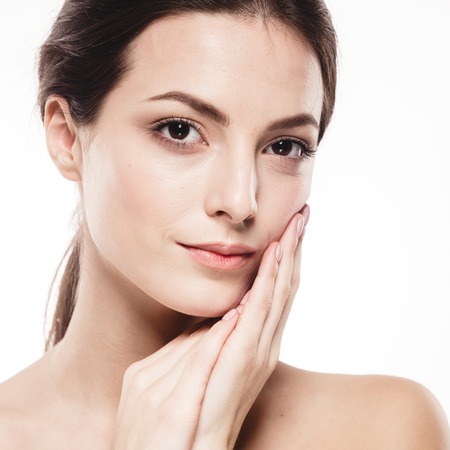 Beauty Woman face Portrait. Beautiful model Girl with Perfect Fresh Clean Skin. Brunette female looking at camera and smiling. Youth and Skin Care Concept. Isolated on a white backgroundの写真素材