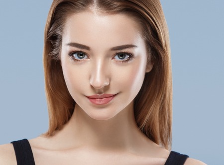 Beautiful woman face close up portrait young studio on blue. Studio shot.の写真素材