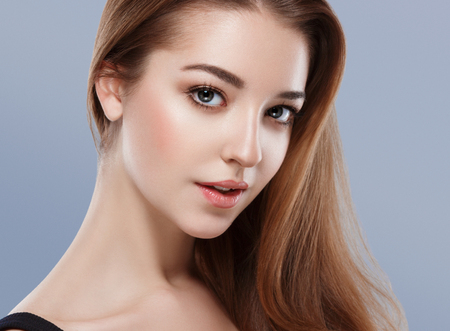 Beautiful woman face close up portrait young studio on blue. Studio shot.の写真素材