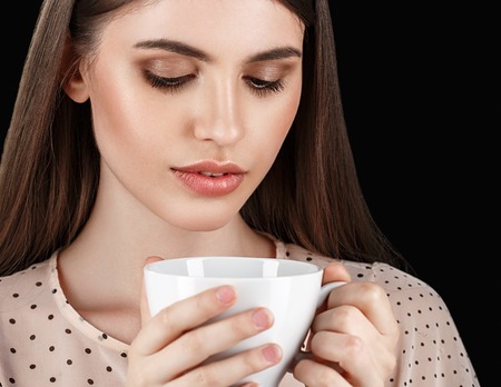 Young beautiful white woman with white cup. Isolated on black background. Studio shot.の写真素材
