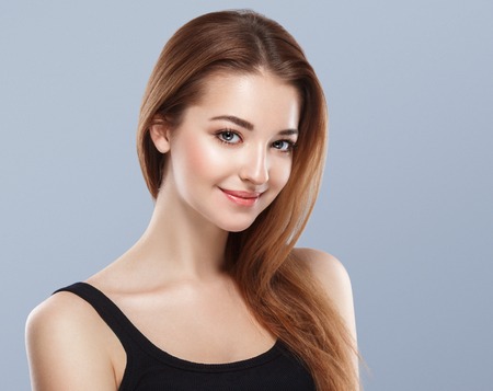 Beautiful woman face close up portrait young studio on blue. Studio shot.の写真素材