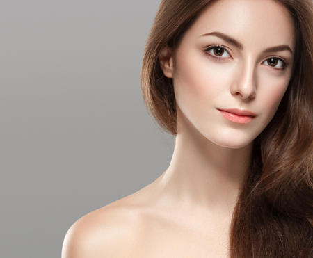 Young beautiful woman face portrait with healthy skin on gray background. Studio shot.の写真素材
