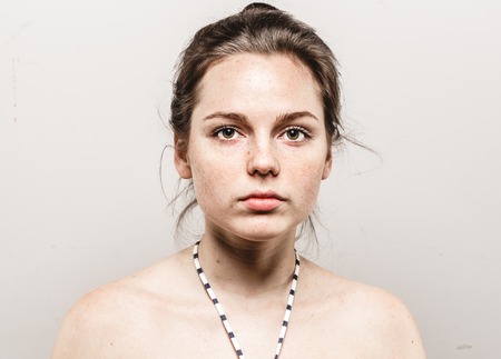 Young beautiful freckles woman face portrait with healthy skin. Studio shot.