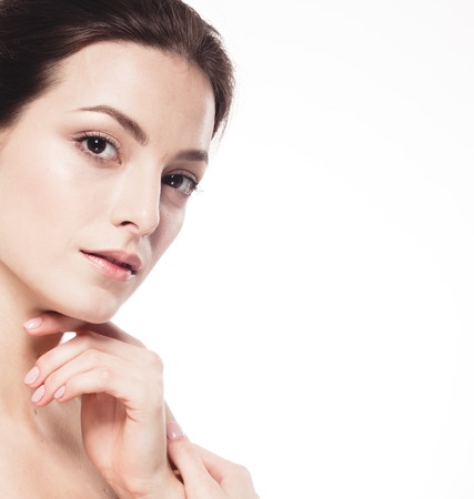 Beauty Woman face Portrait. Beautiful model Girl with Perfect Fresh Clean Skin. Brunette female looking at camera and smiling. Youth and Skin Care Concept. Isolated on a white backgroundの写真素材