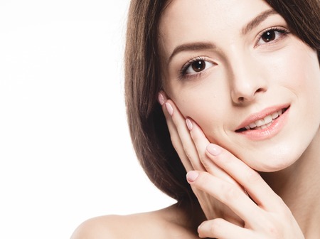 Beauty Woman face Portrait. Beautiful model Girl with Perfect Fresh Clean Skin. Brunette female looking at camera and smiling. Youth and Skin Care Concept. Isolated on a white backgroundの写真素材