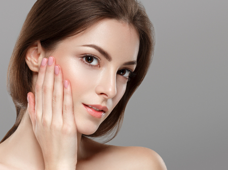 Young beautiful woman face portrait with healthy skin on gray background. Studio shot.の写真素材