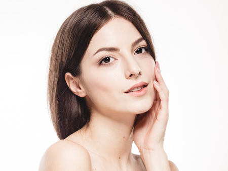 Beauty Woman face Portrait. Beautiful model Girl with Perfect Fresh Clean Skin. Brunette female looking at camera and smiling. Youth and Skin Care Concept. Isolated on a white backgroundの写真素材
