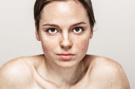 Young beautiful freckles woman face portrait with healthy skin. Studio shot.の写真素材