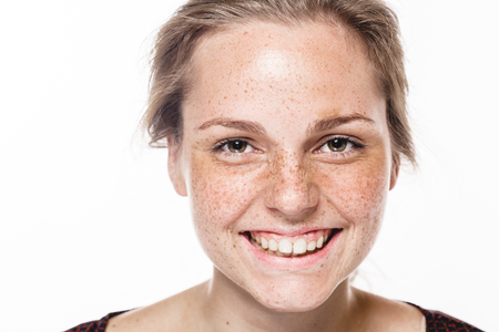 Young beautiful freckles woman face portrait with healthy skin. Studio shot. Isolated on gray.の写真素材