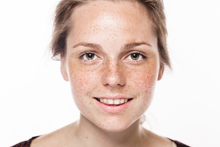 Young beautiful freckles woman face portrait with healthy skin. Studio shot. Isolated on gray.の写真素材