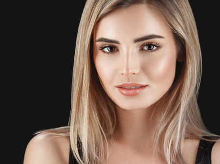 Woman blonde hair closeup beautiful skin portrait on black background. Studio shot.の写真素材