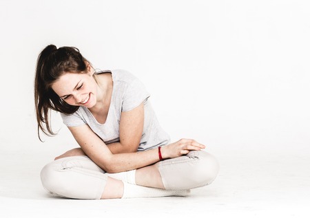 Portrait of a pretty young woman girl sitting on the floor. Isolated on white. Studio shot.の写真素材